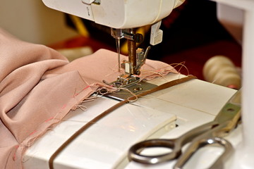 Fabric on the sewing machine. A woman sews a piece of cloth.