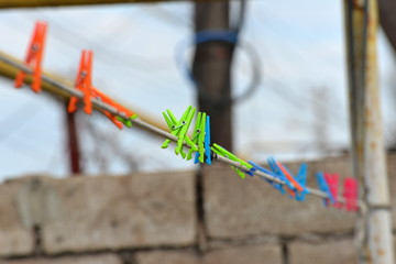 Multicolored plastic clothespins hang on the clothesline of the house.