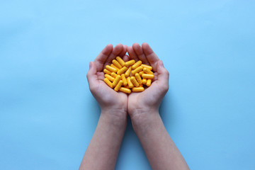 a handful of pills in children's hands on a blue background. concept health. childhood diseases 