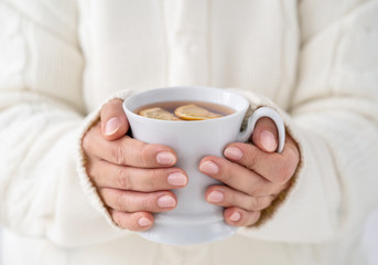 Fototapeta na wymiar Close up of female hands holding cup of hot tee with copy space