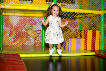 Little child jumping at trampoline in indoors playground. Active toddler girl having fun at sport centre.