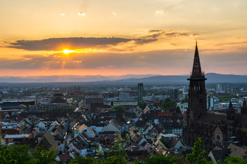 Fototapeta na wymiar Germany, Warm orange evening sunlight on the roofs of City Freiburg im Breisgau from above