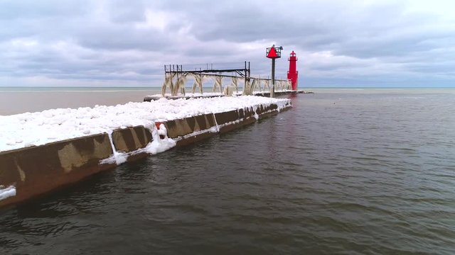 Scenic lighthouse with icicles on pier catwalk after storm, aerial view.
