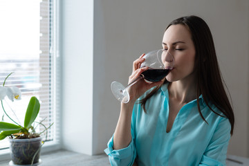 Young woman drinking a glass of red wine. concept of rest after cleaning