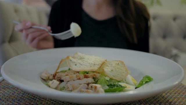 Close up - Female eating Caesar salad at restaurant during lunch break
