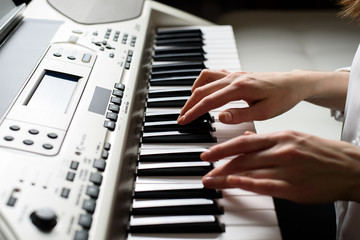 close - up of female hands on the electronic piano in the style of Dead Pan