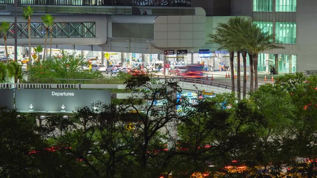 Airport Terminal Building Exterior Timelapse in Miami Florida at Night with Streaking Lights from Driving Cars and Vehicles outside at Arrivals and Departures Areas surrounded by Tropical Palm Trees