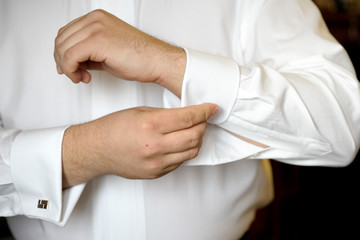 The groom fasten cufflinks on the cuffs of the shirt. The morning gatherings of the groom on the wedding day. Businessman fasten cufflinks on the cuffs of the shirt.