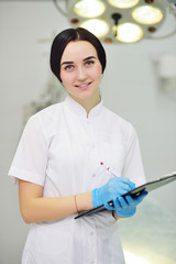 young pretty doctor girl in white medical dressing gown with stethoscope on modern clinic background