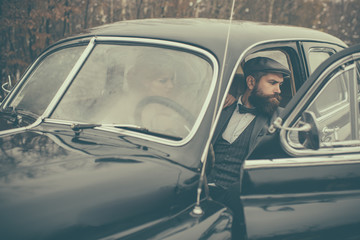 Fototapeta premium Travel and business trip or hitch hiking. Bearded man and sexy woman in car. Escort of girl by security. Couple in love on romantic date. Retro collection car and auto repair by mechanic driver.