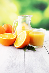 Glass of orange juice and slices of orange fruit on wooden background.