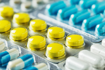 Heap of medical pills in white, yellow and other colors. Herbal medical pills. Pills in plastic...