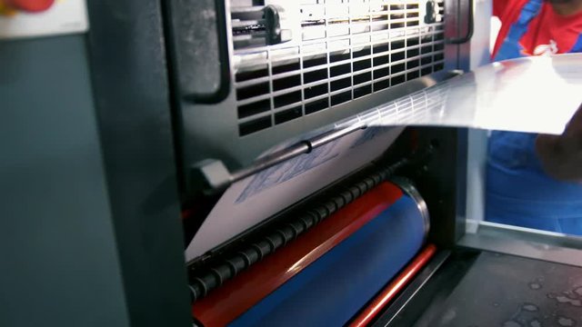 Worker puts the plate in the press print machine