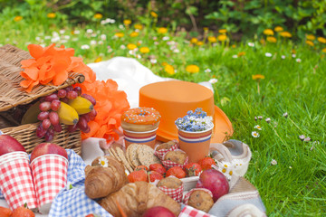 Obraz na płótnie Canvas Picnic in the celebration of the king's day. Lunch in the garden. Basket for a picnic, Fruits and pastries. Orange hat. Spring in the Netherlands. Postcard and text