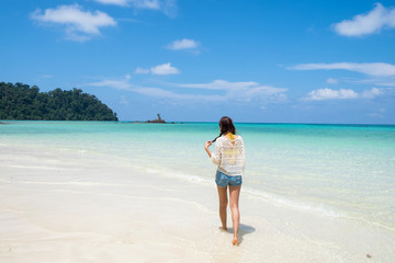 Fototapeta na wymiar Asian young woman walking on white beach in emerald sea