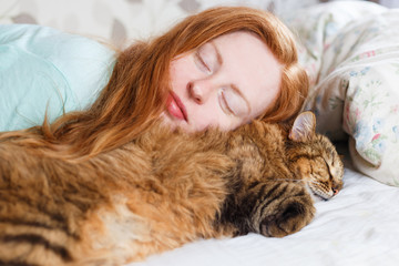 Young redhair woman sleeping with cat