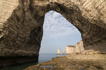 View through the cliff arch over L'Aiguille or the Needle rock and Porte d'Aval at Etretat, a commune in the Seine-Maritime department in the Normandy region of north western France