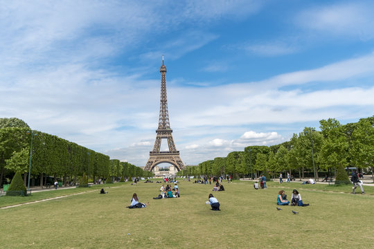 Paris, France - circa May, 2017: Lots of people relaxing and having fun on Champ de Mars with the Eiffel Tower on background on a sunny day