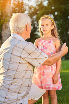 Girl with her grandpa outdoors. Child and senior man.