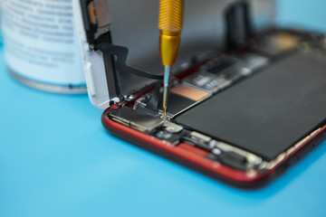 Close up shot of disassembled damaged smart phone being repaired with precision screwdriver in...