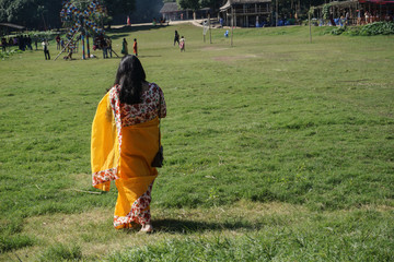girl in yellow saree walking on green grass