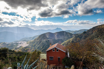 Fototapeta na wymiar Green landscape with cloudy sky and small house among mountains in Andalusia, Spain