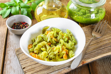Pasta with pesto sauce on an old wooden table.