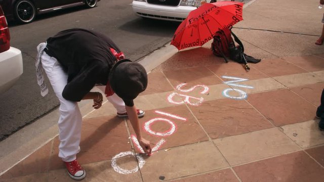 Man chalks "No SB 1070" on sidewalk in Phoenix, Arizona