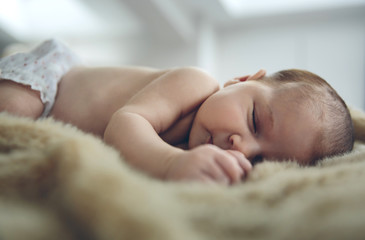 Obraz na płótnie Canvas Newborn baby girl sleeping lying on a blanket on the bed