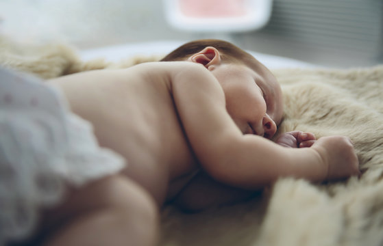 Newborn baby girl sleeping lying on a blanket on the bed