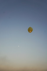 yellow sky lantern flying into sunset