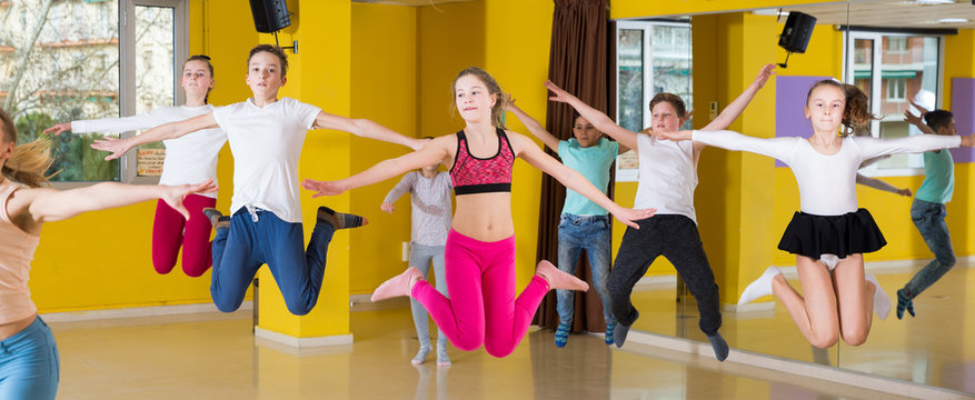Children with teacher jumping in dance hall
