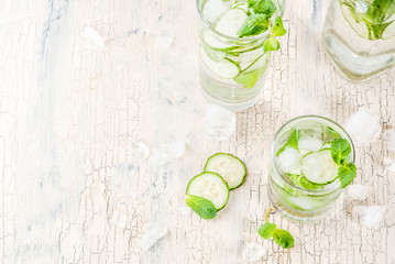 Obraz premium Summer fresh iced drink, mint and cucumber infused water, summer healthy detox mojito cocktail, light background copy space