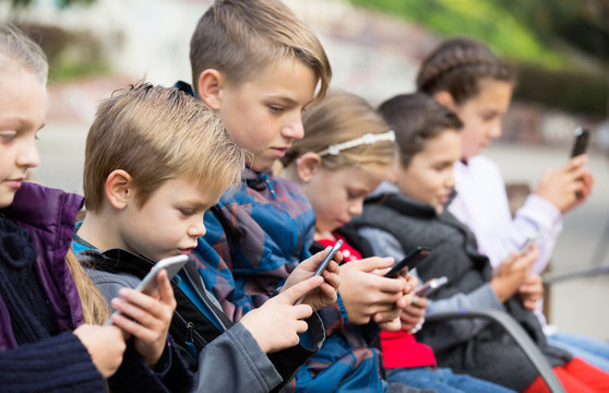 Children sitting on bench with tablets