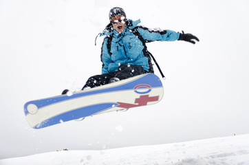 Fototapeta na wymiar Snowboarder jumping through air with gray sky