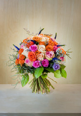 bouquet of flowers, multi-colored roses with green leaves stands on a light white table