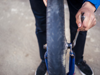 close up bike wheel repairing, hand tighten a nut