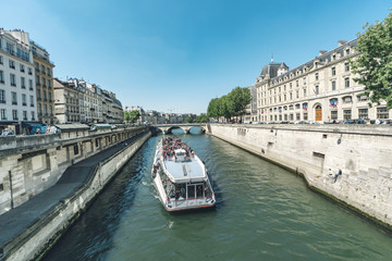 Fototapeta na wymiar Paris, France- circa May, 2017: Tourist boat at narrow chanel near Notre Dame with bridge Pont Saint-Michel over river Seine in Paris, France