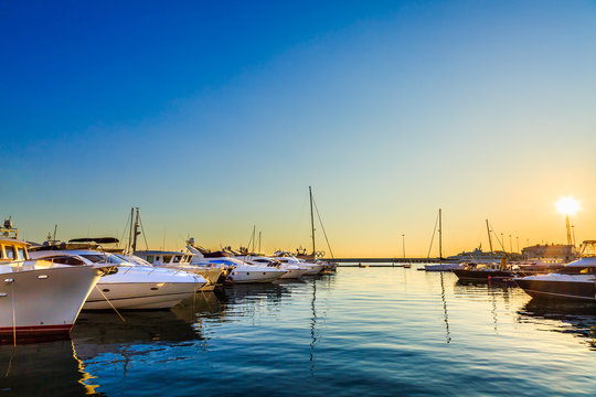 Fototapeta Luxury yachts, sailing and motor boats docked in sea port at sunset.
