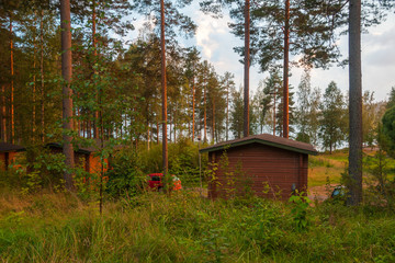 Wooden houses in forest by lake at sunset, Finland 