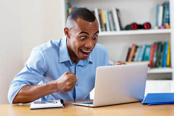 Obraz na płótnie Canvas Cheering african american man at computer