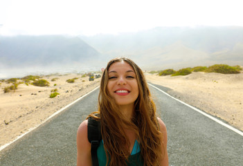 Freedom concept. Portrait of young woman in the middle of desert asphalt road highway in Lanzarote Island, Spain
