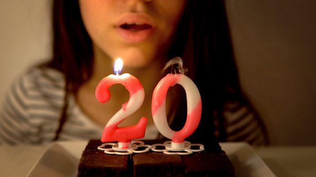 Girl Blowing Out A 20th Birthday Candle On A Cupcake