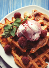 Waffles with raspberry ice cream and fresh raspberries, decorated with mint over blue wooden background