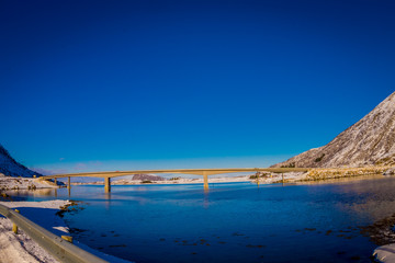 Astonishing outdoor view of Gimsoystraumen Bridge is a cantilever road that crosses the strait between the islands of Austvagoya and Gimsoya in a beautiful blue sky