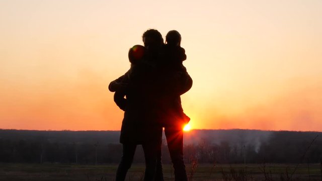 Mom, Dad and daughter on sunset background. 