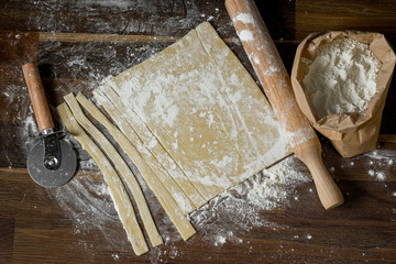 Top view of a dough stripped pastry for cooking homemade pasta recipe on a wooden table background, home cooking concept, close-up, flat lay. - 202106001