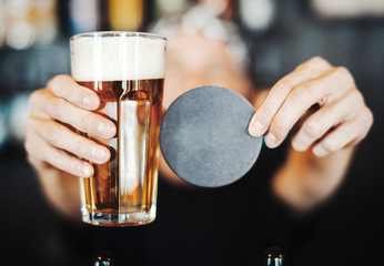 Bartender man stretches out glass of beer and beerdeckel.