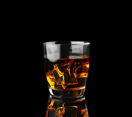 Whiskey with ice on black.