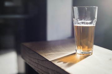 Glass of beer on wooden table at bar.